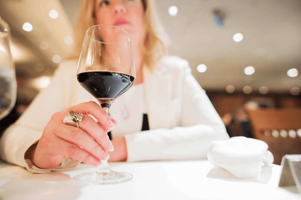 Eine Frau im Restaurant mit einem Glas Rotwein in der Hand. 